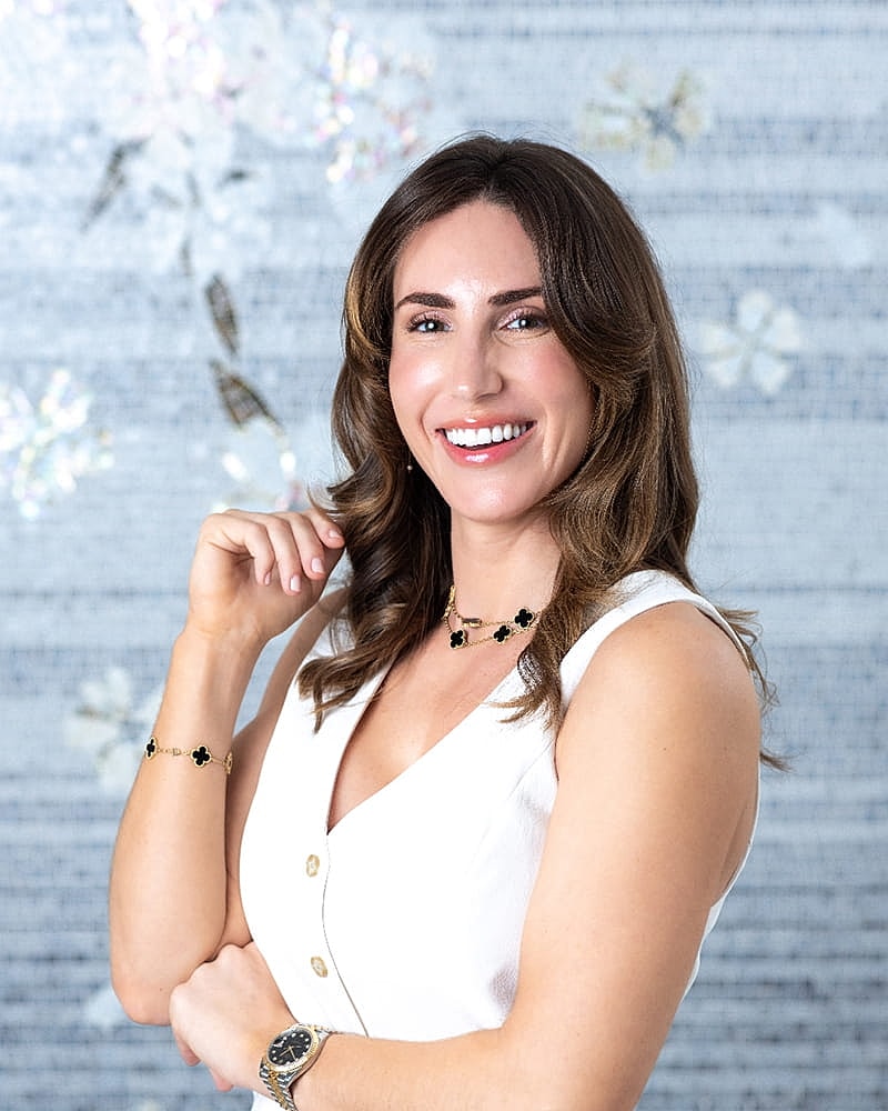 Smiling woman in white dress with jewelry.